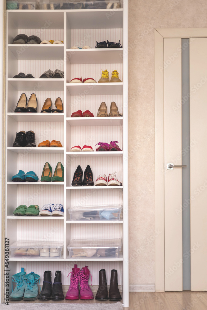 Empty domestic wardrobe interior with many female shoes neatly folded on shelves of cupboard