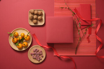 Tangerines and nuts on a red table with a gift box for preparing new year.setting and decoration ideas for the lunar festival and Chinese new year background