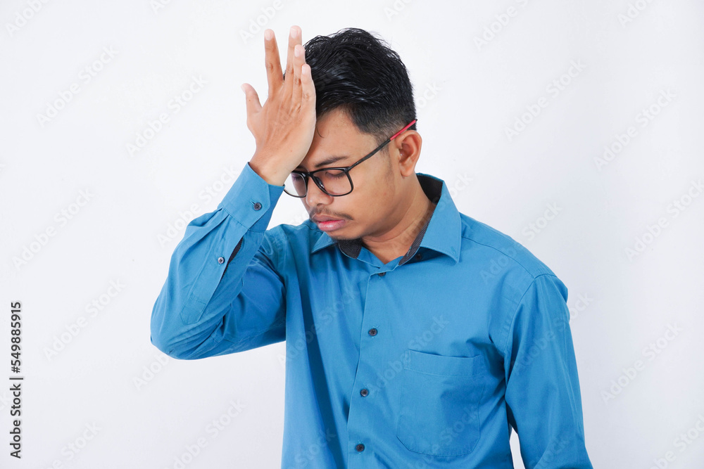 Handsome young asian businessman with glasses in wearing blue shirt forgetting something, slapping forehead with palm isolated on white background Handsome young asian businessman with glasses in wearing blue shirt forgetting something, slapping forehead with palm isolated on white background