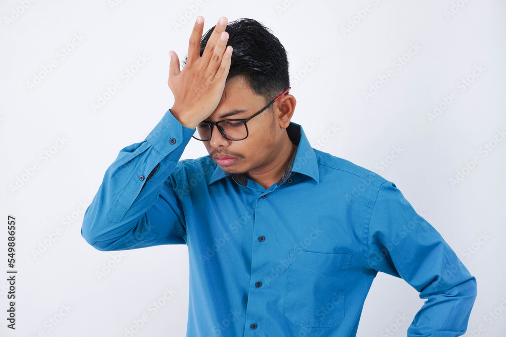 Handsome young asian businessman with glasses in wearing blue shirt forgetting something, slapping forehead with palm isolated on white background Handsome young asian businessman with glasses in wearing blue shirt forgetting something, slapping forehead with palm isolated on white background