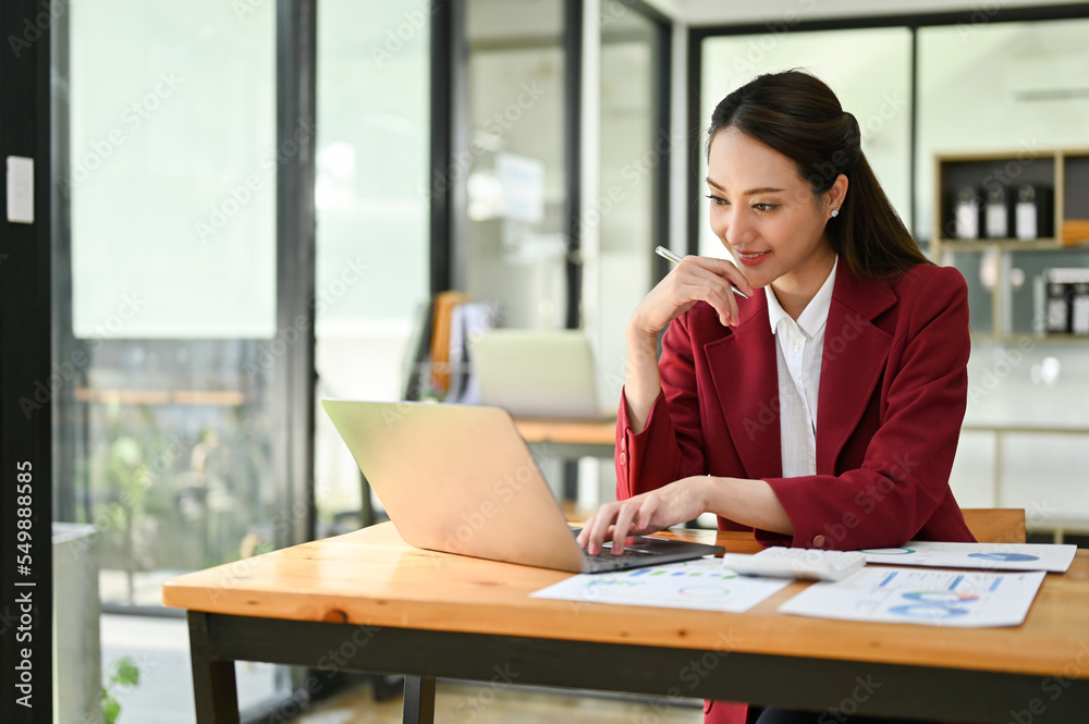Asian businesswoman working at her desk, hand on chin, using laptop, thinking and planning project. Asian businesswoman working at her desk, hand on chin, using laptop, thinking and planning project.