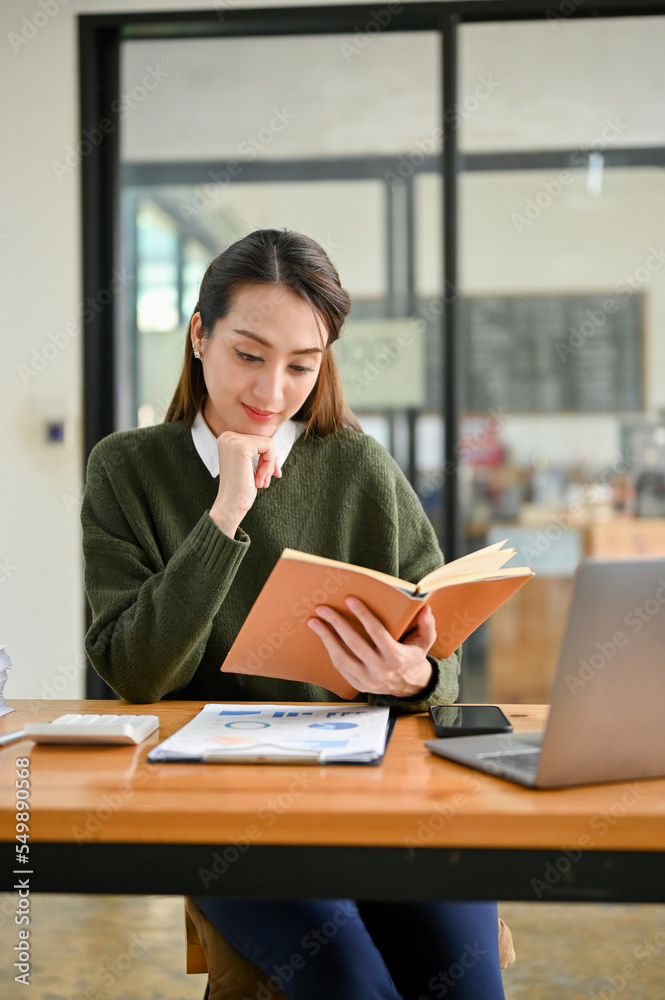 Portrait, Asian businesswoman or female financial worker reading a book at her office desk. Portrait, Asian businesswoman or female financial worker reading a book at her office desk.