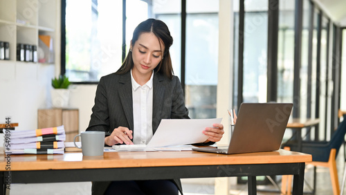 Wallpaper Mural Professional Asian female accountant focusing on her sales accounts, using calculator Torontodigital.ca