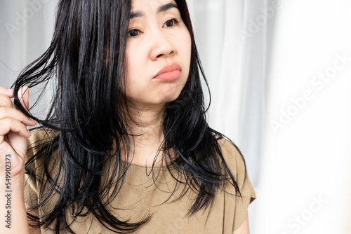 stress Asian woman have problems with oily hair and thinning hair looking at the mirror