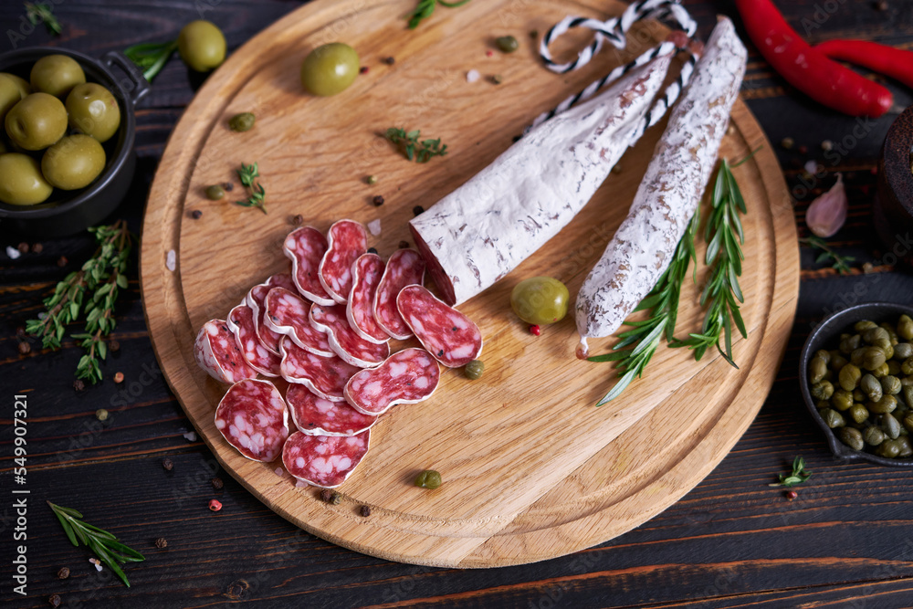 Spanish fuet salami sausageon wooden cutting board at domestic kitchen Spanish fuet salami sausageon wooden cutting board at domestic kitchen