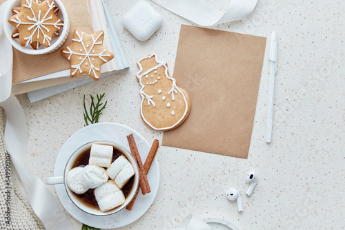 Mock up of crafting envelope near earphones. Warm cocoa with marshmallows and homemade ginger cookies in shape of cute snowflakes. Aesthetic female Christmas background