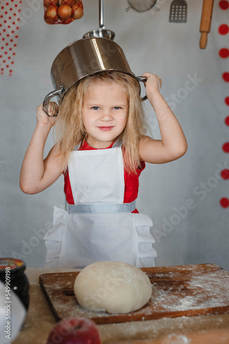 little girl in the kitchen with a pot on her head