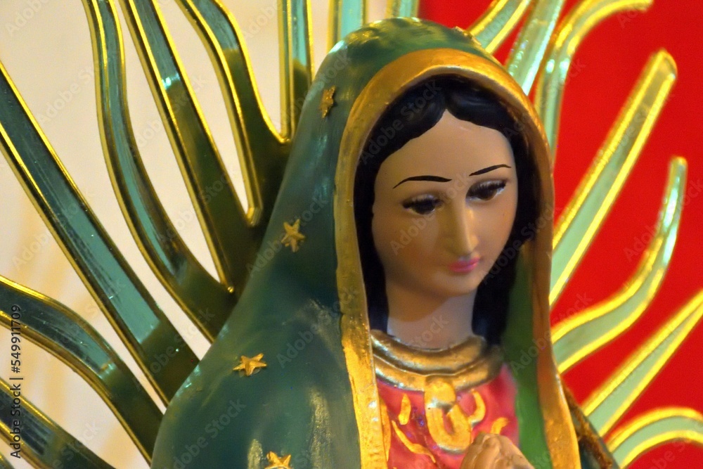 Altar to of Our Lady of Guadalupe with candles, mexican colors and flowers ready to recieve