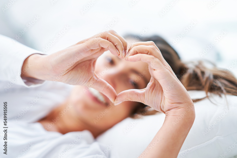 Young nice woman on the bed showing heart Young nice woman on the bed showing heart