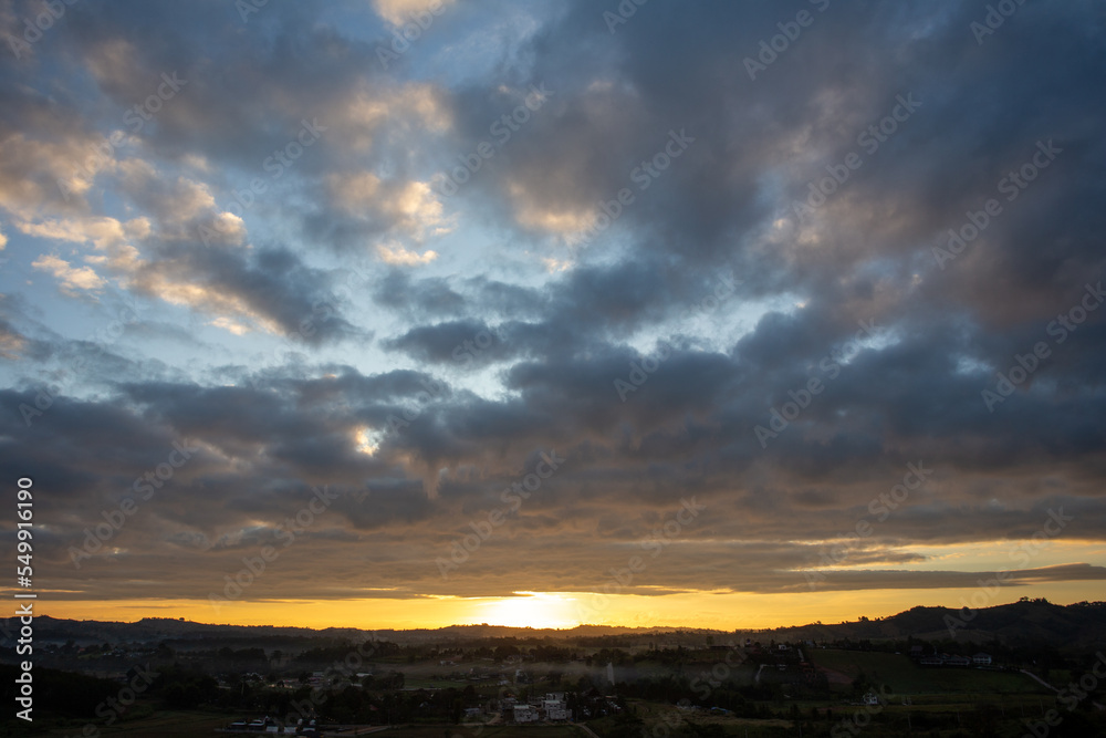 Morning view at morning sunrise, clouds in orange crimson colors. Silhouettes of houses roofs, trees, and a monastery on the hill. Colorful scenery skyline background.