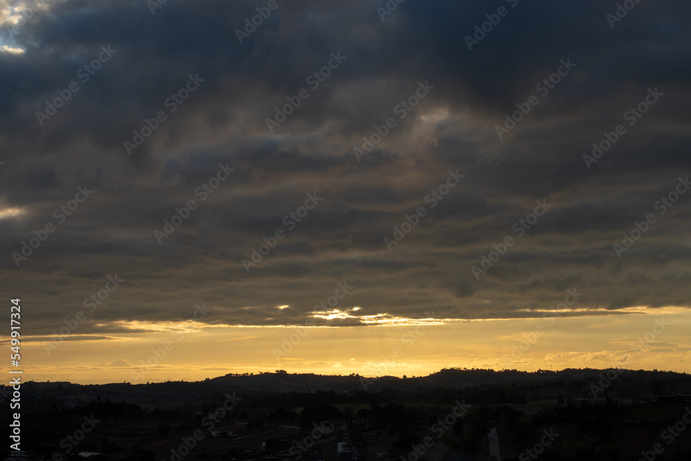 Morning view at morning sunrise, clouds in orange crimson colors. Silhouettes of houses roofs, trees, and a monastery on the hill. Colorful scenery skyline background. Morning view at morning sunrise, clouds in orange crimson colors. Silhouettes of houses roofs, trees, and a monastery on the hill. Colorful scenery skyline background.
