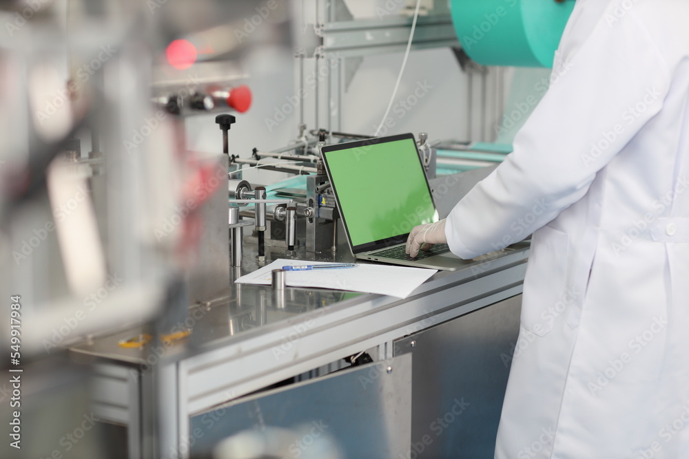 Inspector man or worker male hands doing quality of mask and medical face mask production line with blank green screen computer, Industry and factory concept.