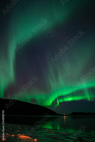 Aurora borealis in the starry night sky over the lake