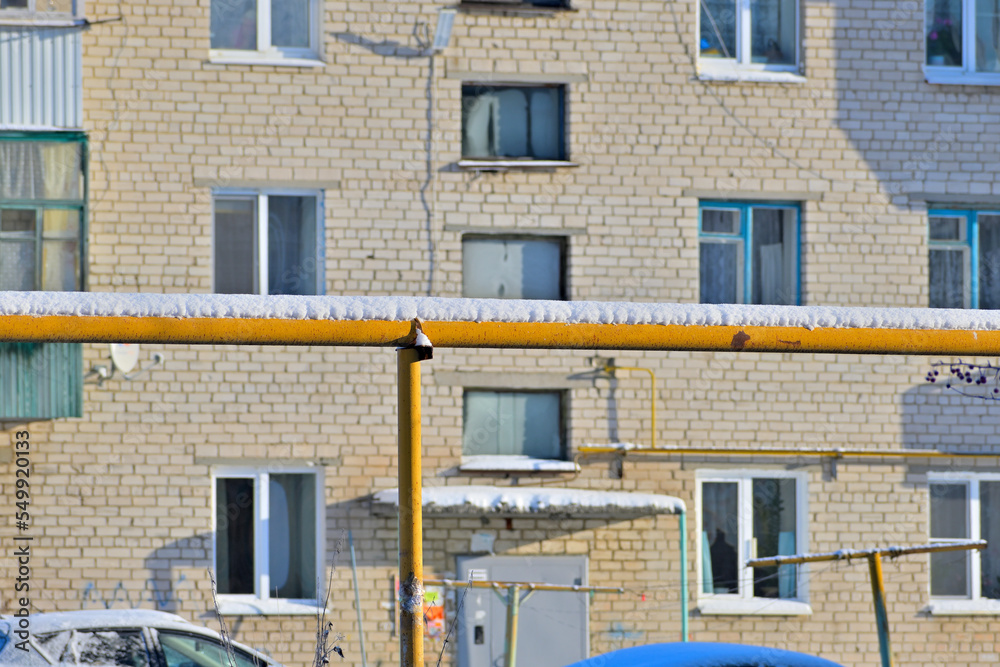 A snow-covered gas pipe on the background of a residential building on a winter day