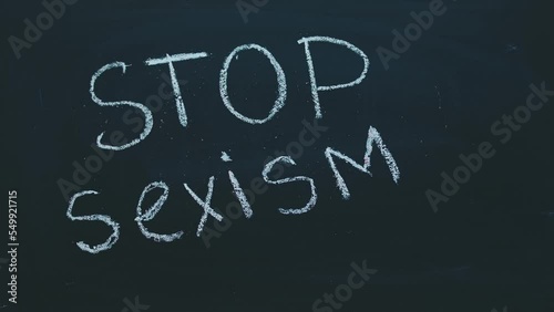 Close-up of a timelapse of a child's hand writing with chalk on a blackboard stop sexism. The concept of feminism, acceptance and women's rights photo