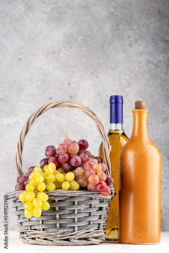 Ripe grape in basket and wine bottles