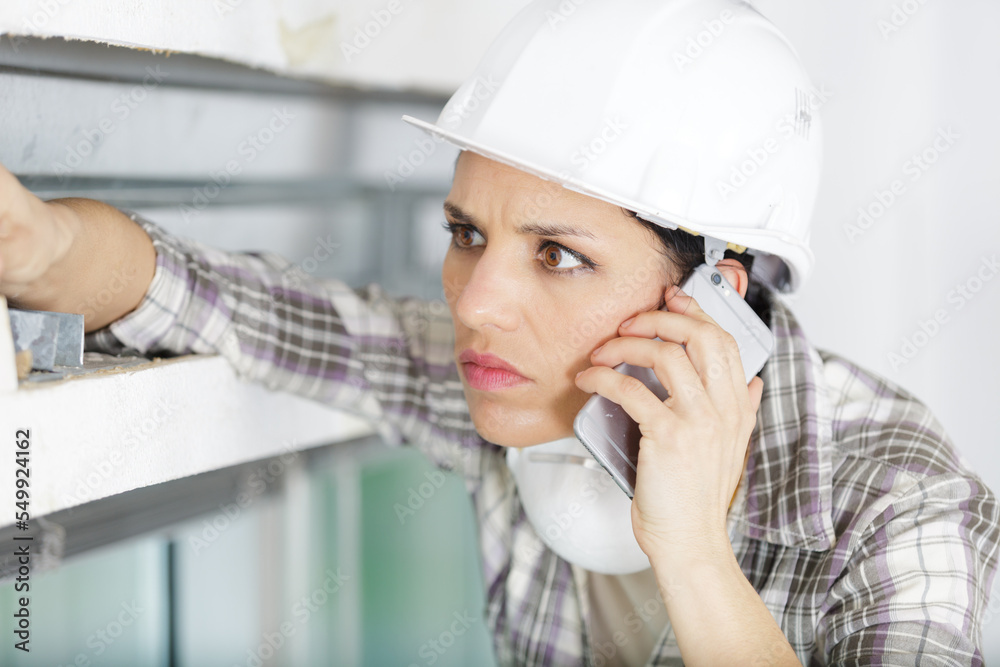 concerned female builder using smartphone concerned female builder using smartphone
