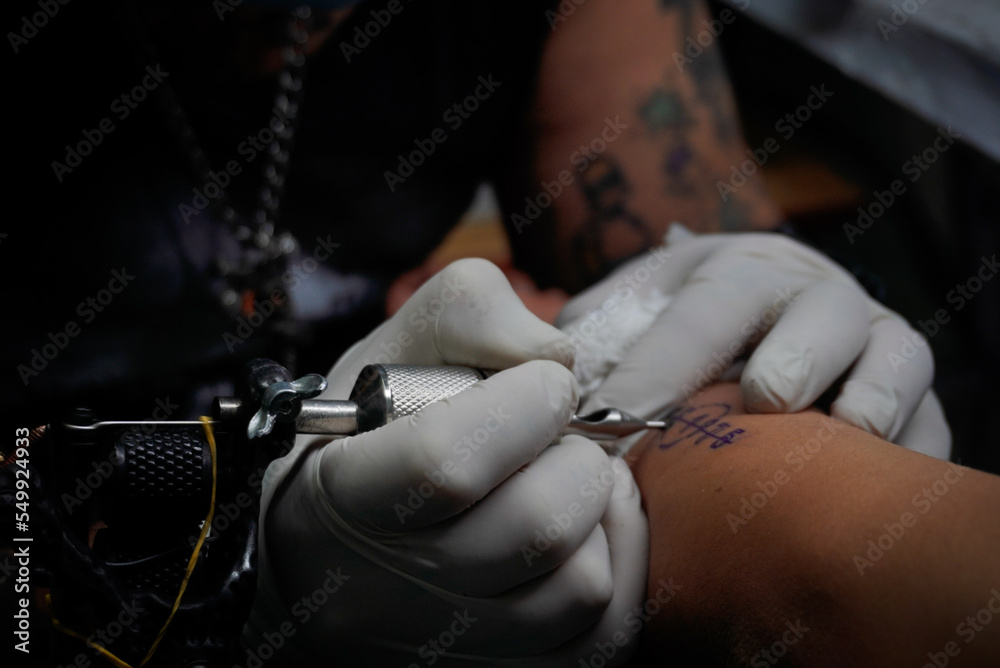 Artista Del Tatuaje Aplica Tatuaje Al Brazo. Ella Está Llenando De Tinta  Negra El Tatuaje. Fotos, retratos, imágenes y fotografía de archivo libres  de derecho. Image 183923979