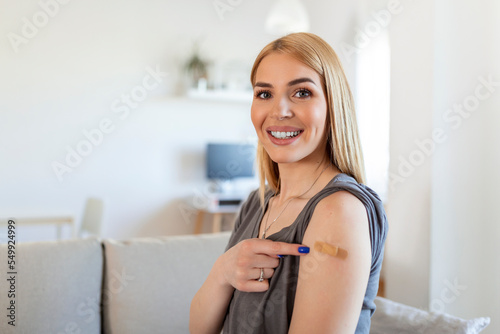 Woman pointing at his arm with a bandage after receiving the vaccine. Young woman showing her shoulder after getting cvaccine photo