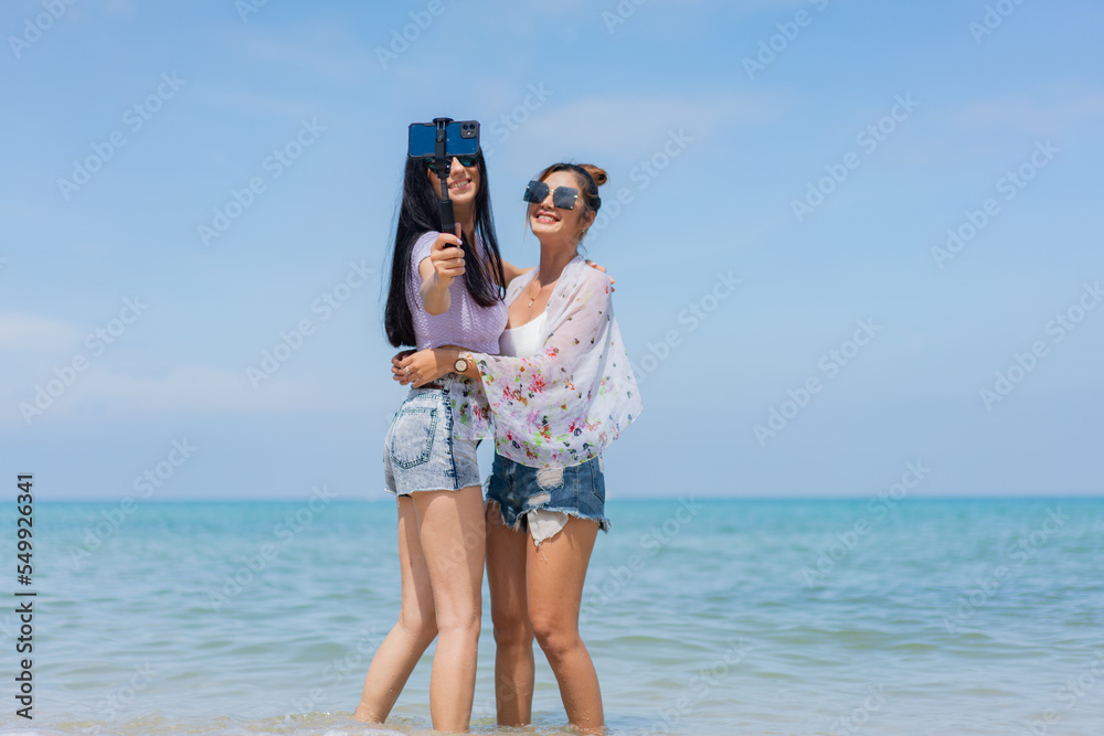 Two girlfriends hugging up and enjoying on the sea beach. A pair of girls in love cuddling on a tropical beach. romantic young lesbian couples in love and walking together on the beach.Concept of LGBT Two girlfriends hugging up and enjoying on the sea beach. A pair of girls in love cuddling on a tropical beach. romantic young lesbian couples in love and walking together on the beach.Concept of LGBT