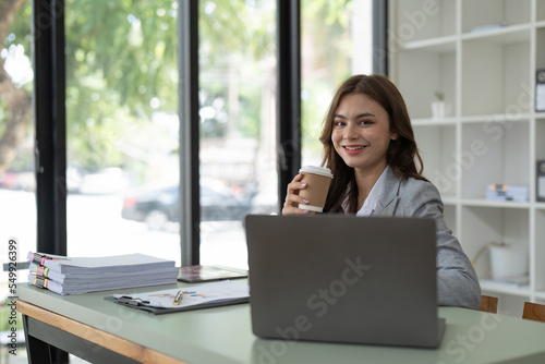 Charming young business woman with a smile working on laptop computer at office