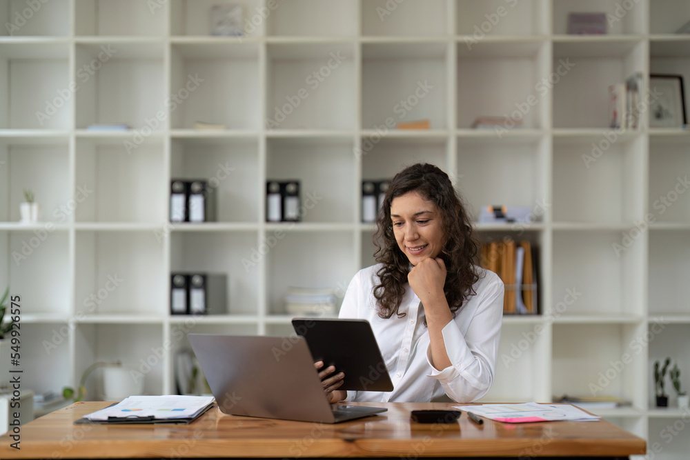 Pretty, charming woman using, browsing, typing, searching, expertising, working online on computer and tablet in workplace, using wi-fi internet Pretty, charming woman using, browsing, typing, searching, expertising, working online on computer and tablet in workplace, using wi-fi internet
