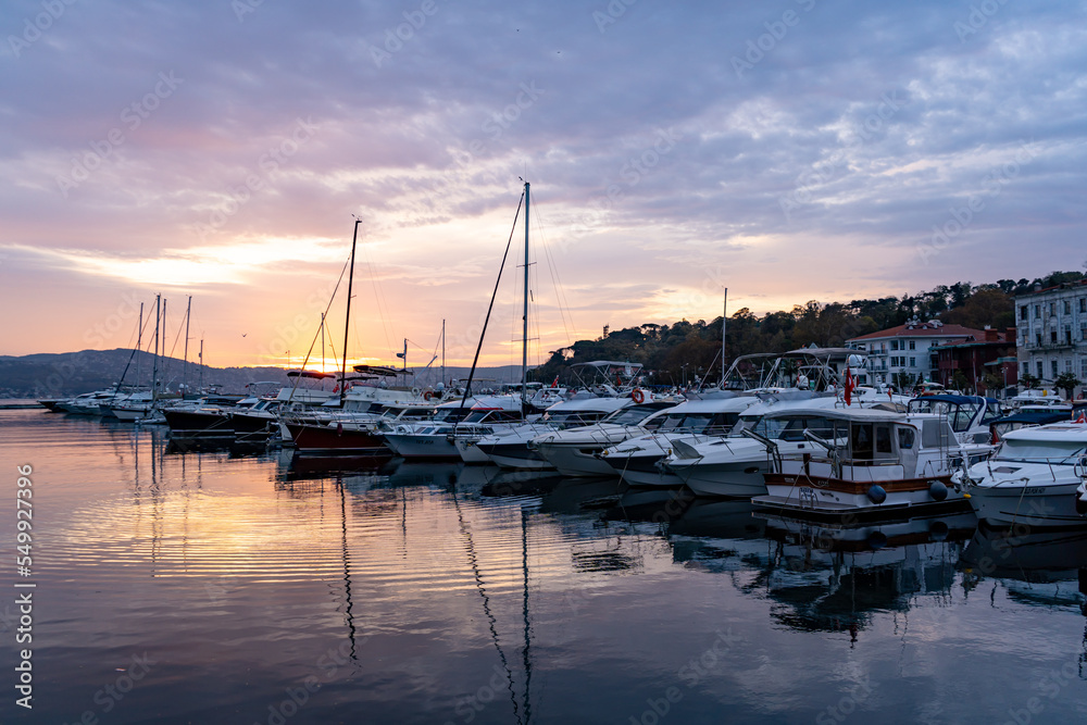 Sailboats at Tarabya yacht marina in Istanbul. Reflection of yachts and hotel. Blue sky and natural white clouds.	