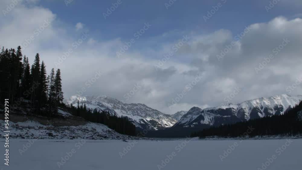 Time lapse of the frozen Upper Kananaskis Lake in winter day with clouds and blue sky Time lapse of the frozen Upper Kananaskis Lake in winter day with clouds and blue sky