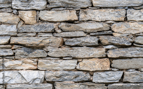 A stonewall made with gray granite slabs cut to various sizes.