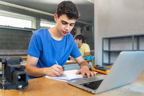 Teenager male student writing exercise in the technology science course