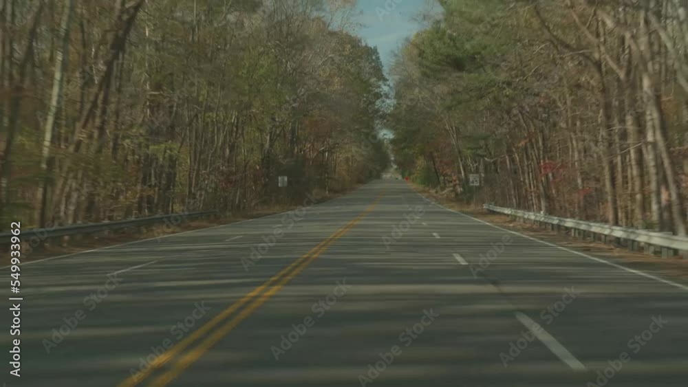 Driving down a four-lane highway lined with autumn trees. Driving down a four-lane highway lined with autumn trees.