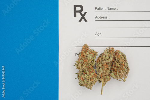 Dry marijuana buds flower over the medical prescription sheet on a blue background