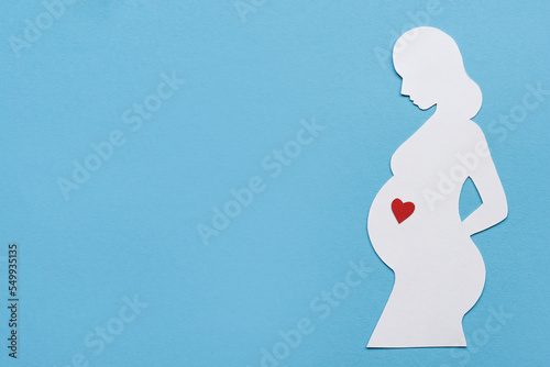 A banner about pregnancy and motherhood. Silhouette of a pregnant woman on blue background and space for text. Minimalist design, flat lay.
