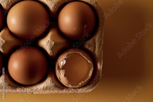 The poster concept is not like everyone else's. A broken egg in a cardboard package with other eggs. Yellow background, selective focus. Close-up photo