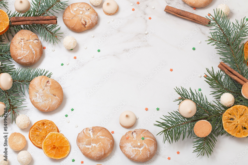 candies and cookies with christmas tree branches on white marble background candies and cookies with christmas tree branches on white marble background
