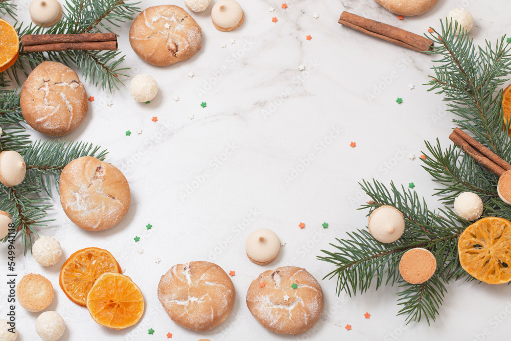 candies and cookies with christmas tree branches on white marble background