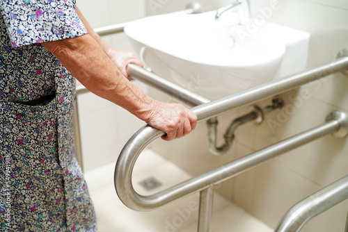Obraz na plátne Asian elderly old woman patient use toilet support rail in bathroom, handrail safety grab bar, security in nursing hospital