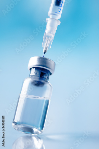 фотографія Glass vial and syringe with injection over blue background