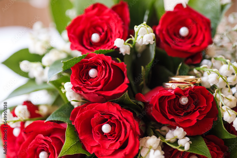 Hochzeitsringe auf roten Rosen und Maiglöckchen Hochzeitsringe auf roten Rosen und Maiglöckchen