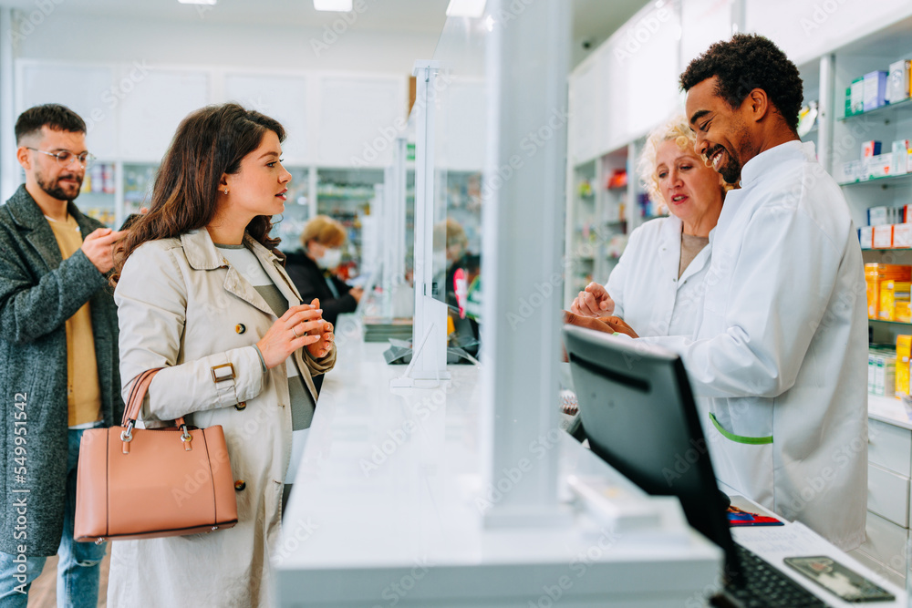 Naklejka premium Pregnant woman talking to pharmacists at drugstore.