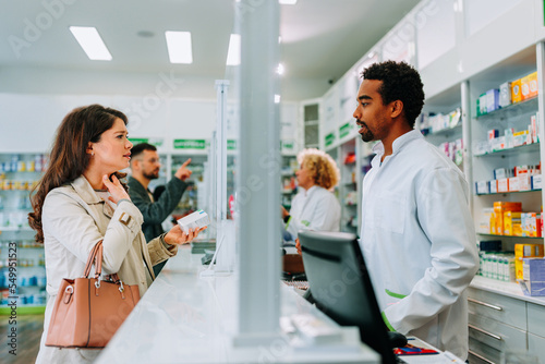 Woman with sore throat in pharmacy. photo