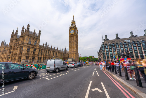 Long exposure of the Houses of Parliament in London with blue sky seen from Westminster Bridge with some blurred people.