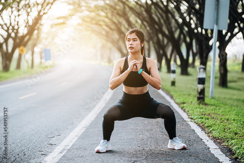 Beautiful fitness asian woman doing squat sit up exercise workout at sport stadium. Attractive female warming up body training wearing sportswear. Healthy and active lifestyle concept.