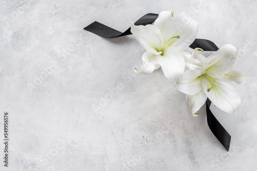 Mourning or funeral concept with white liles and black ribbon photo