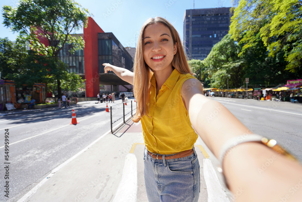 Fototapeta premium Travel in Sao Paulo, Brazil. Beautiful smiling girl takes self portrait on Paulista Avenue, Sao Paulo, Brazil.