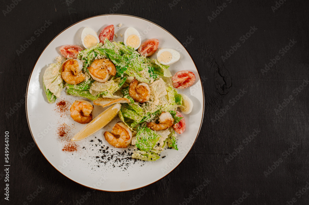 Tasty salad with shrimps, herbs and vegetables on black background Tasty salad with shrimps, herbs and vegetables on black background