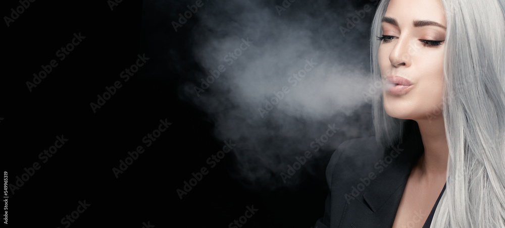 Vaping girl. Gorgeous silver haired woman blowing smoke, isolated on black background with copy space
