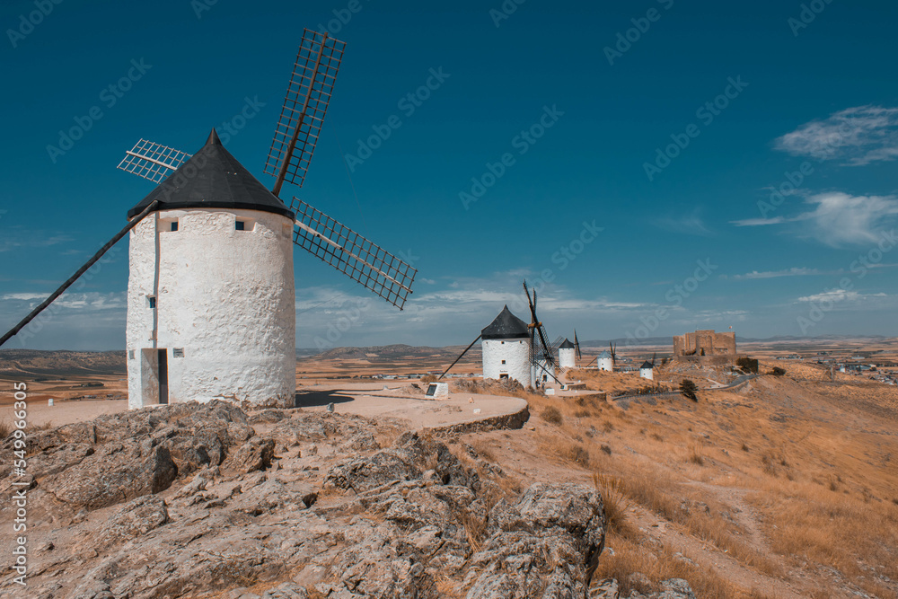 Windmills of La Mancha, Spain and castle in distance. Aerial view flying past blades.
