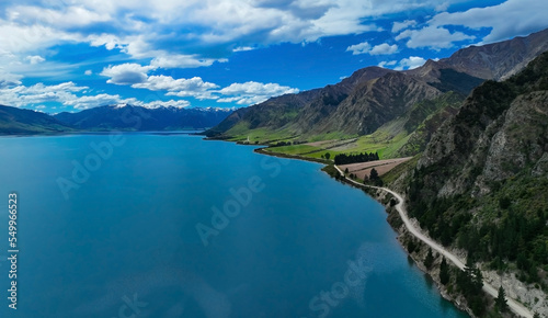 Aerial view of road between green forest and blue hawea lake New zealand