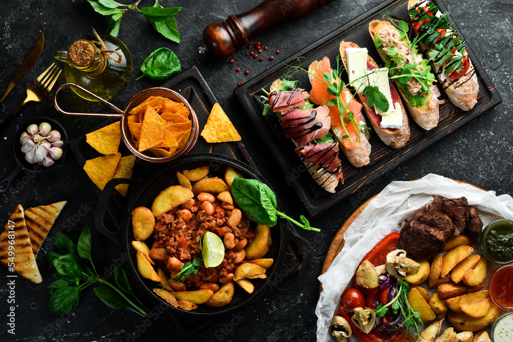 Fototapeta premium Food. Baked potatoes with meat and a set of sandwiches. On a black stone background.